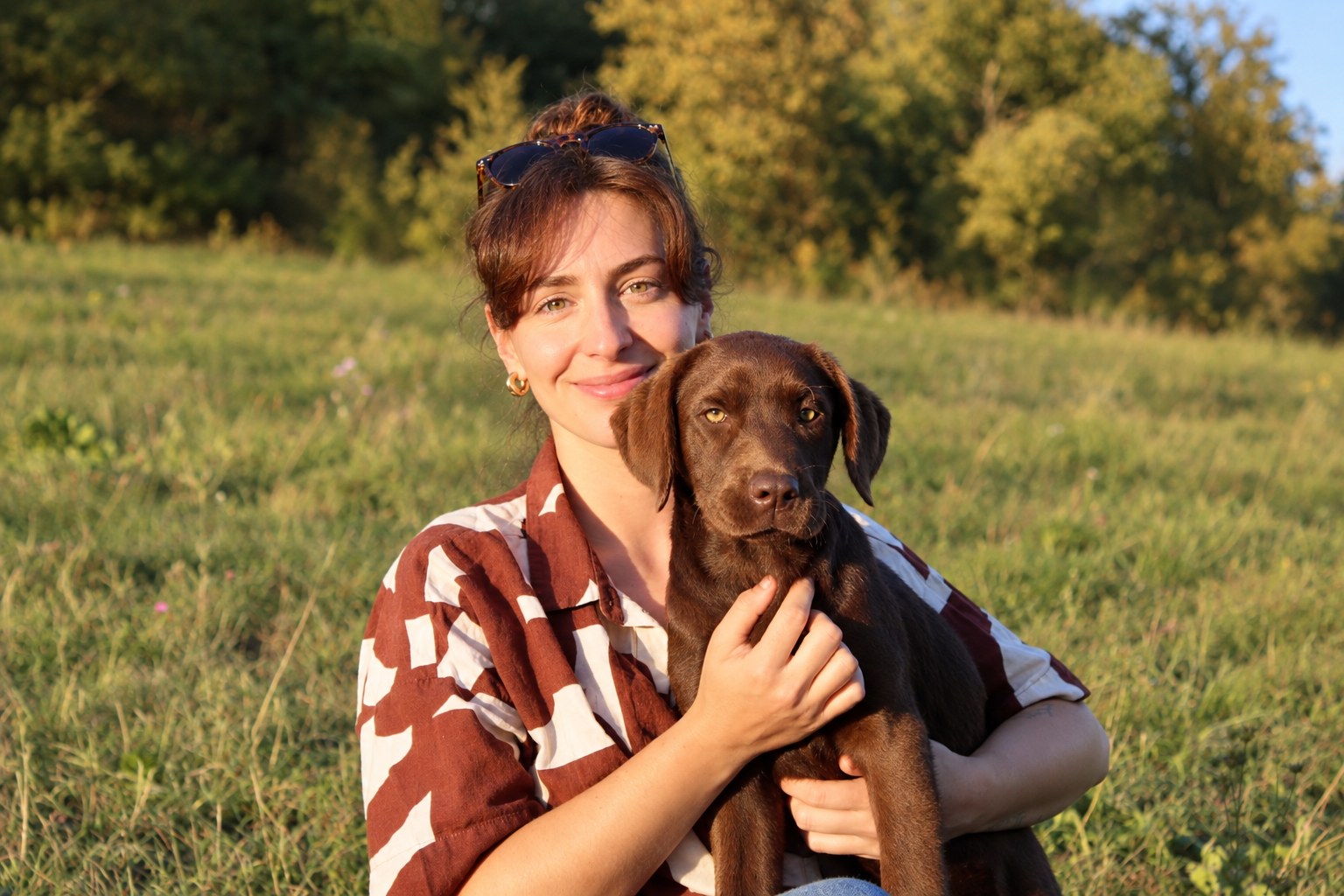 Clémentine Daillet avec sa chienne Bertille, chiot Labrador chocolat, dans la prairie